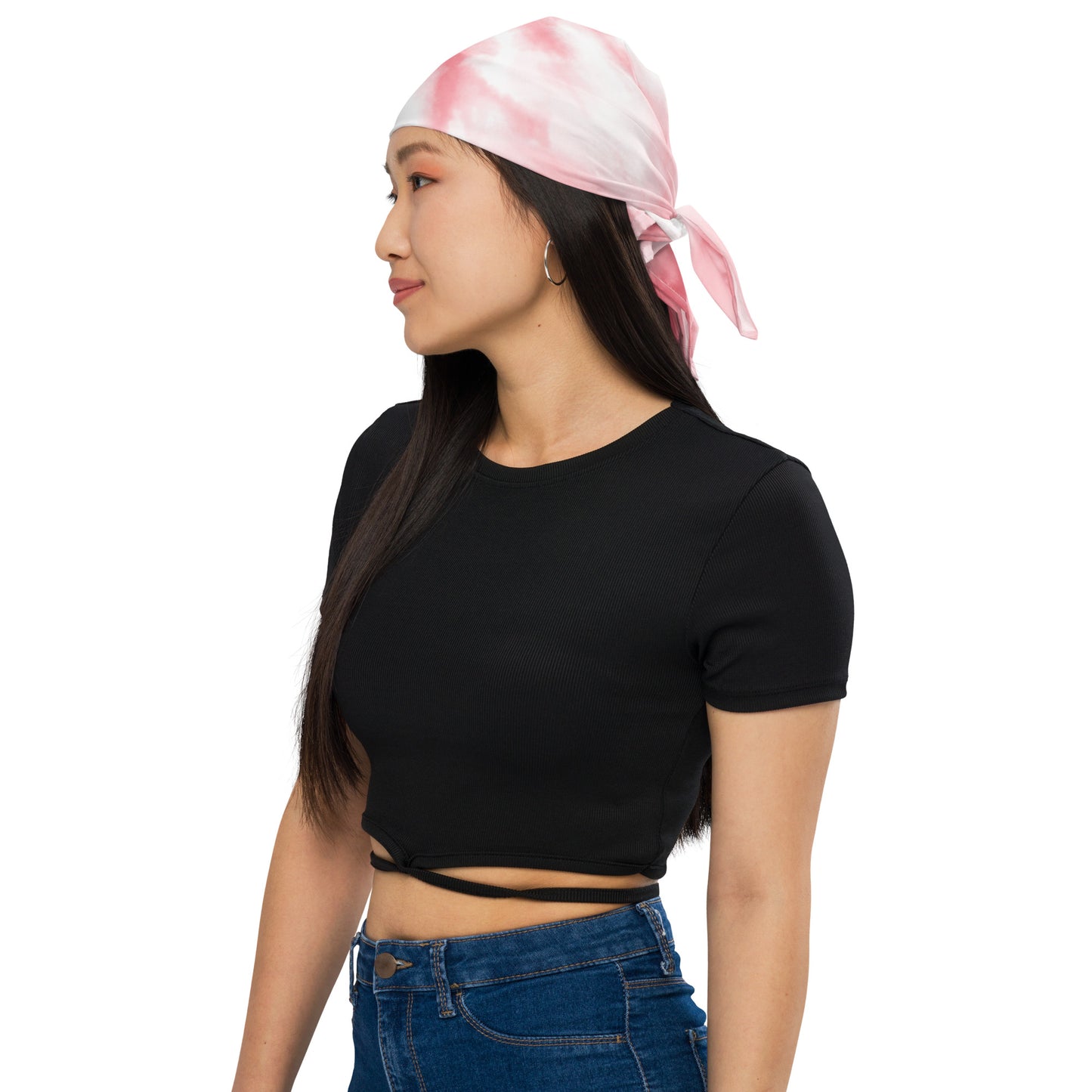 Woman wearing a black crop top and blue jeans with a pink and white headscarf on a white background