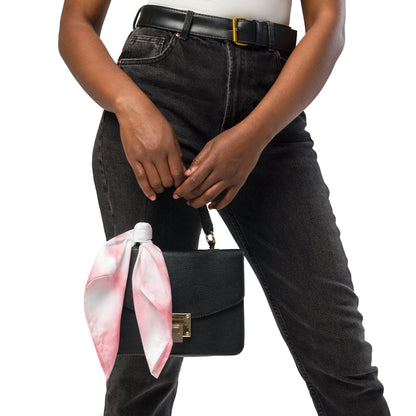 Person holding a black handbag with a pink scarf, wearing black jeans and a white top.